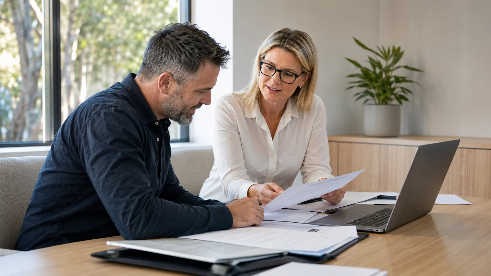 An accountant reviews financial papers with a small-business client in Australia