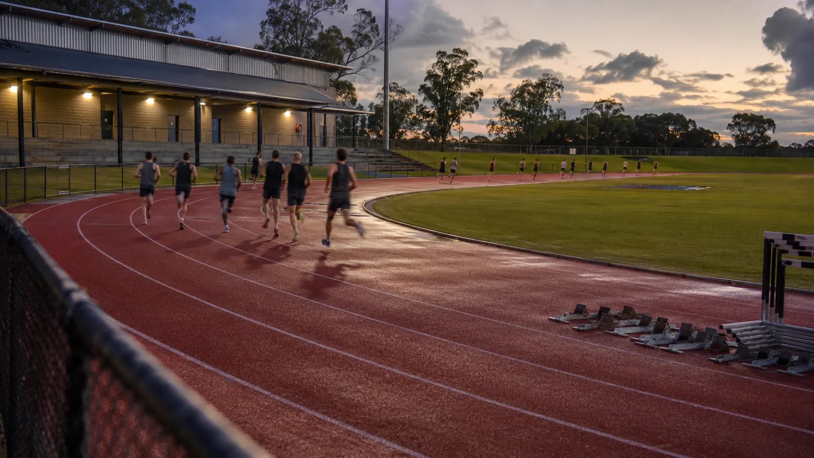 Athletes train around a sunlit red running track in Australia