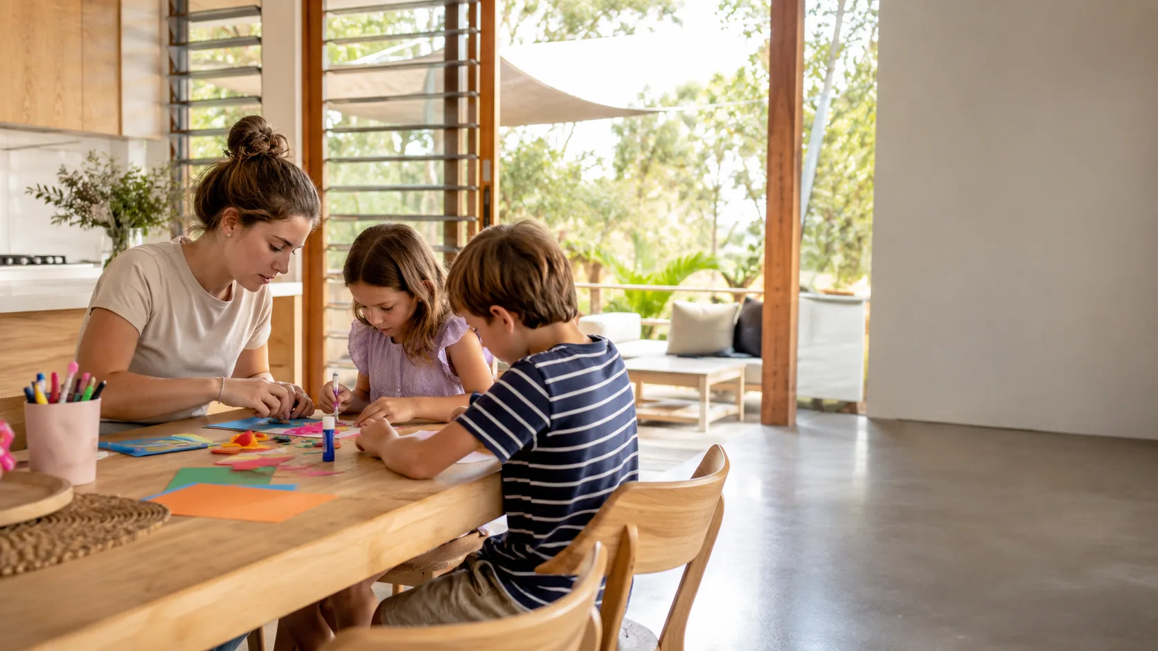 A sitter does craft at the kitchen table with two children in an Australian home