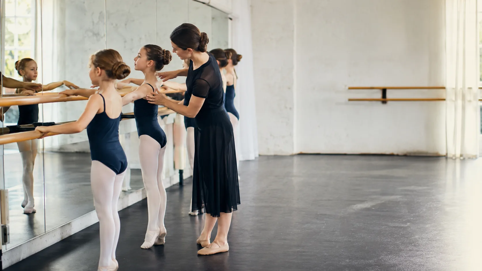 Ballet teacher guiding young dancers at the barre in an Australian studio