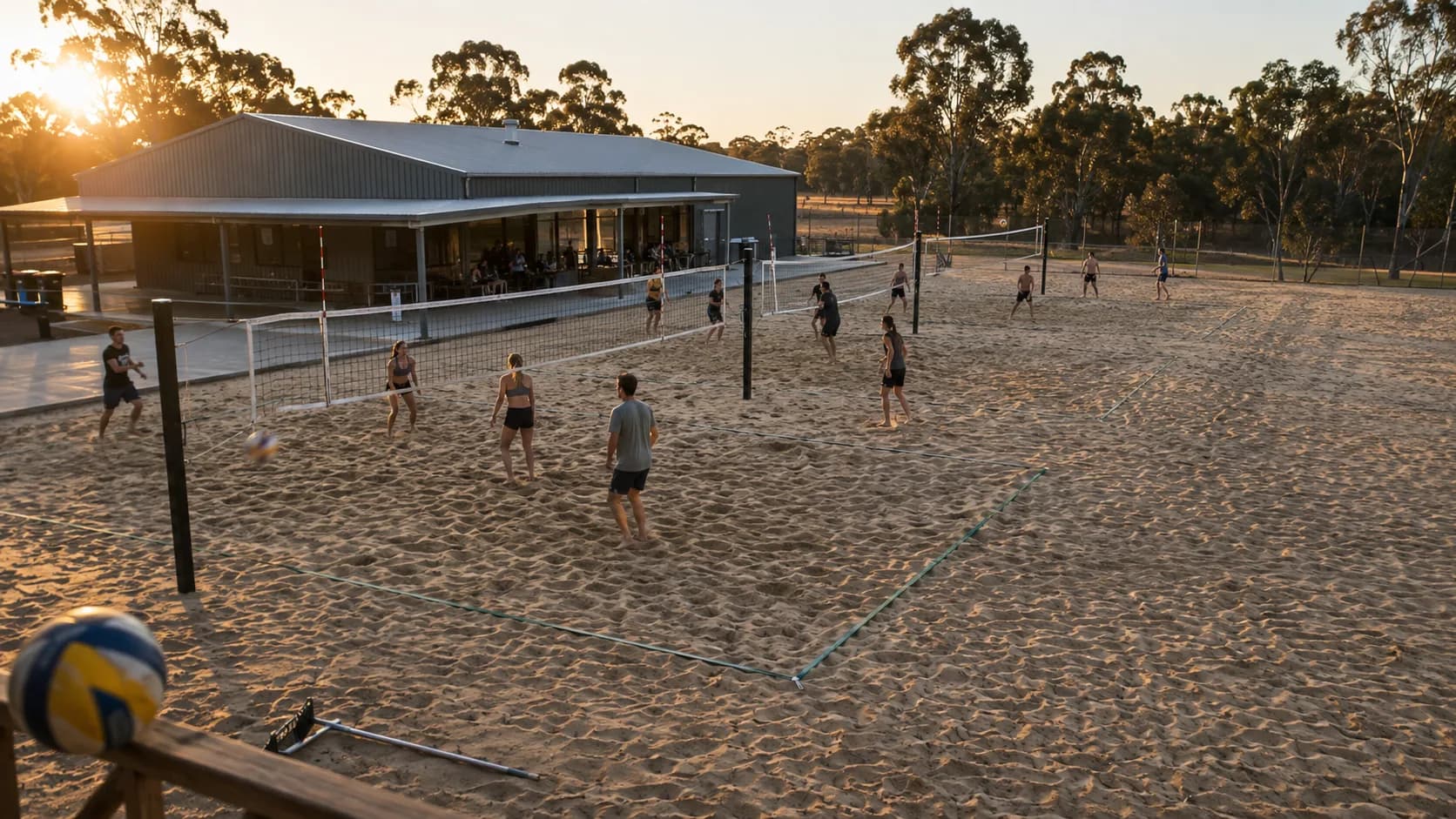 Players rally across busy beach volleyball courts beside an Australian pavilion
