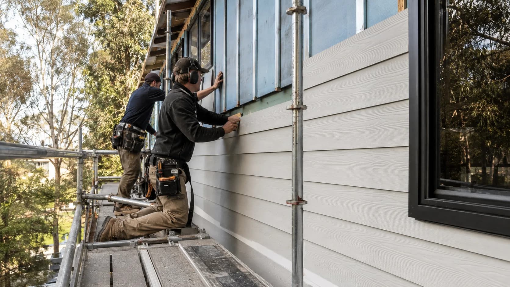 Installers hanging cladding boards on a house in Australia