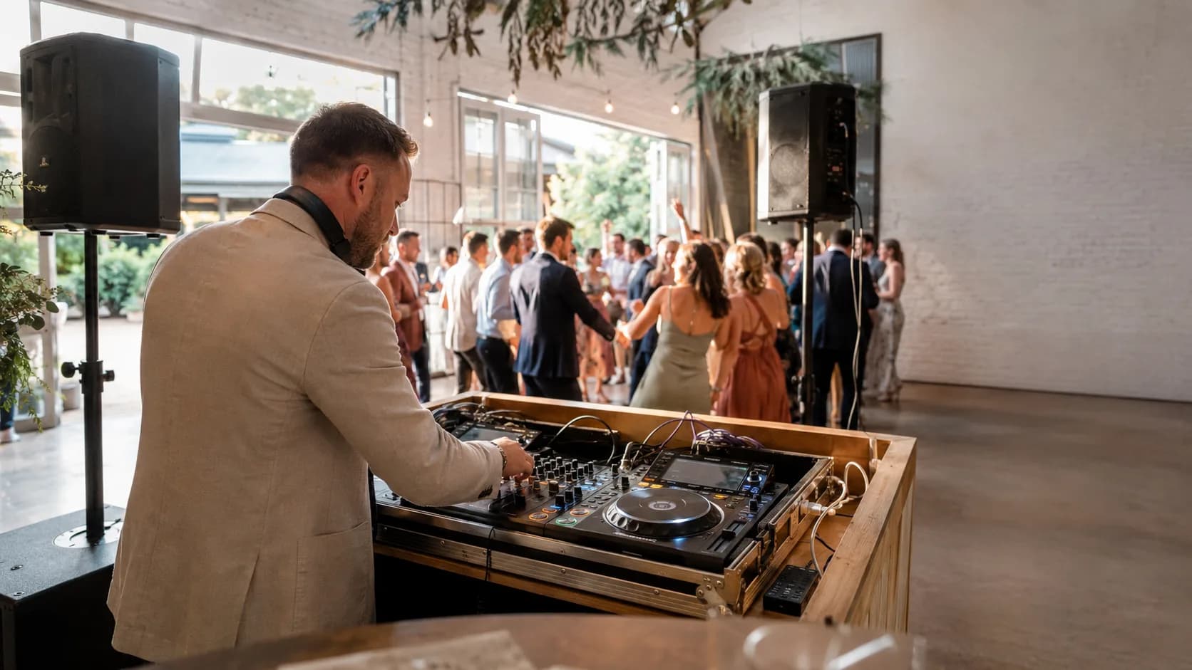 Professional DJ mixing beside a busy wedding dance floor in Australia