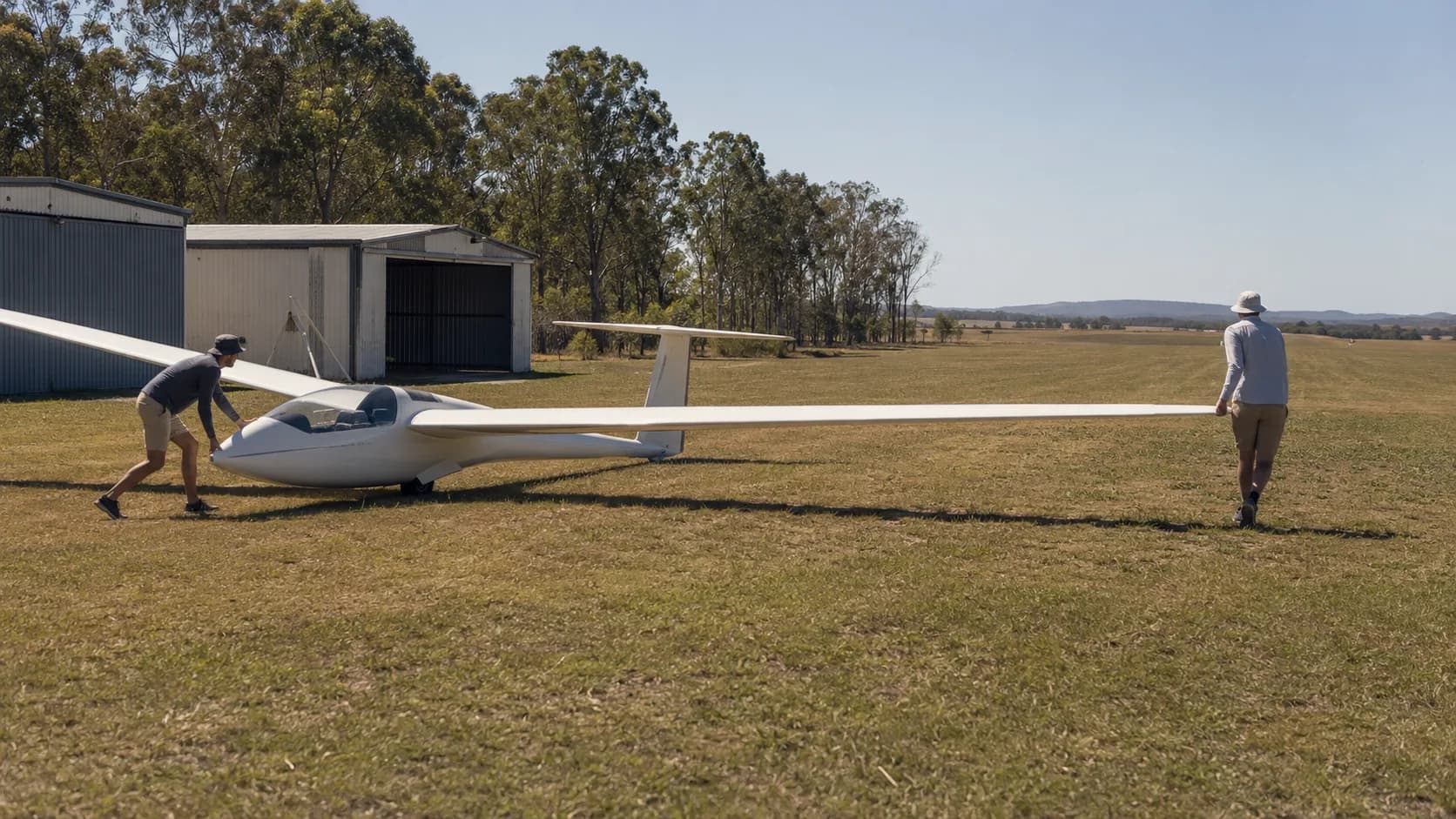 A glider waits on an Australian country strip with a tow plane ahead of it