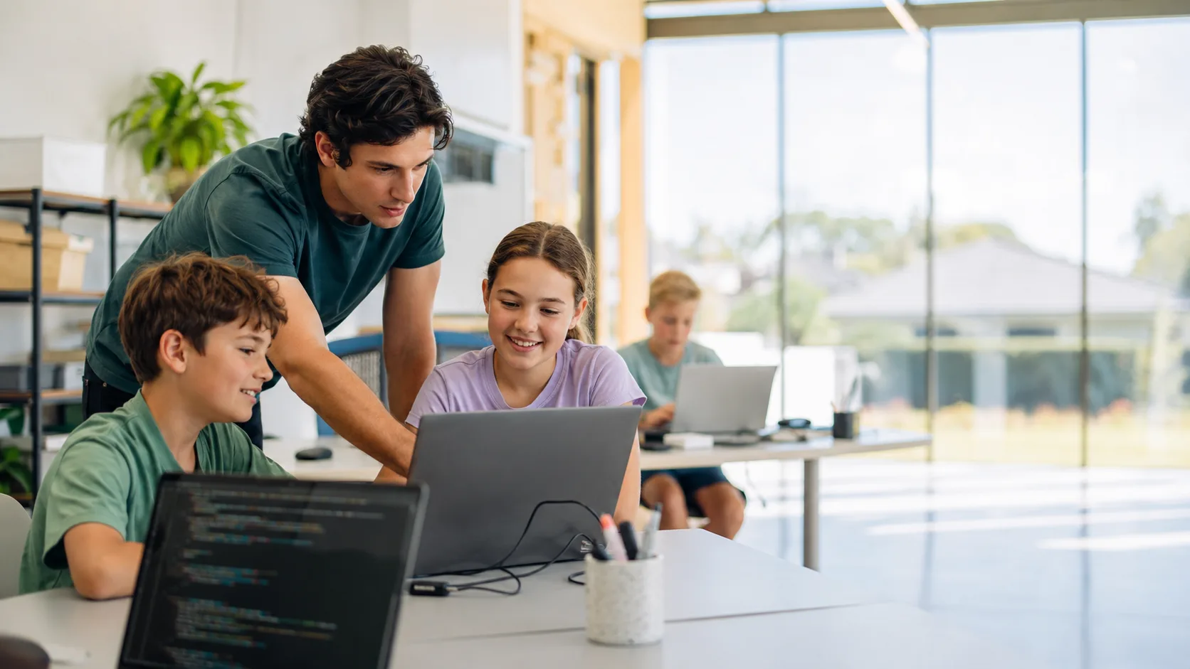Tutor helping children code at laptops in an Australian learning studio