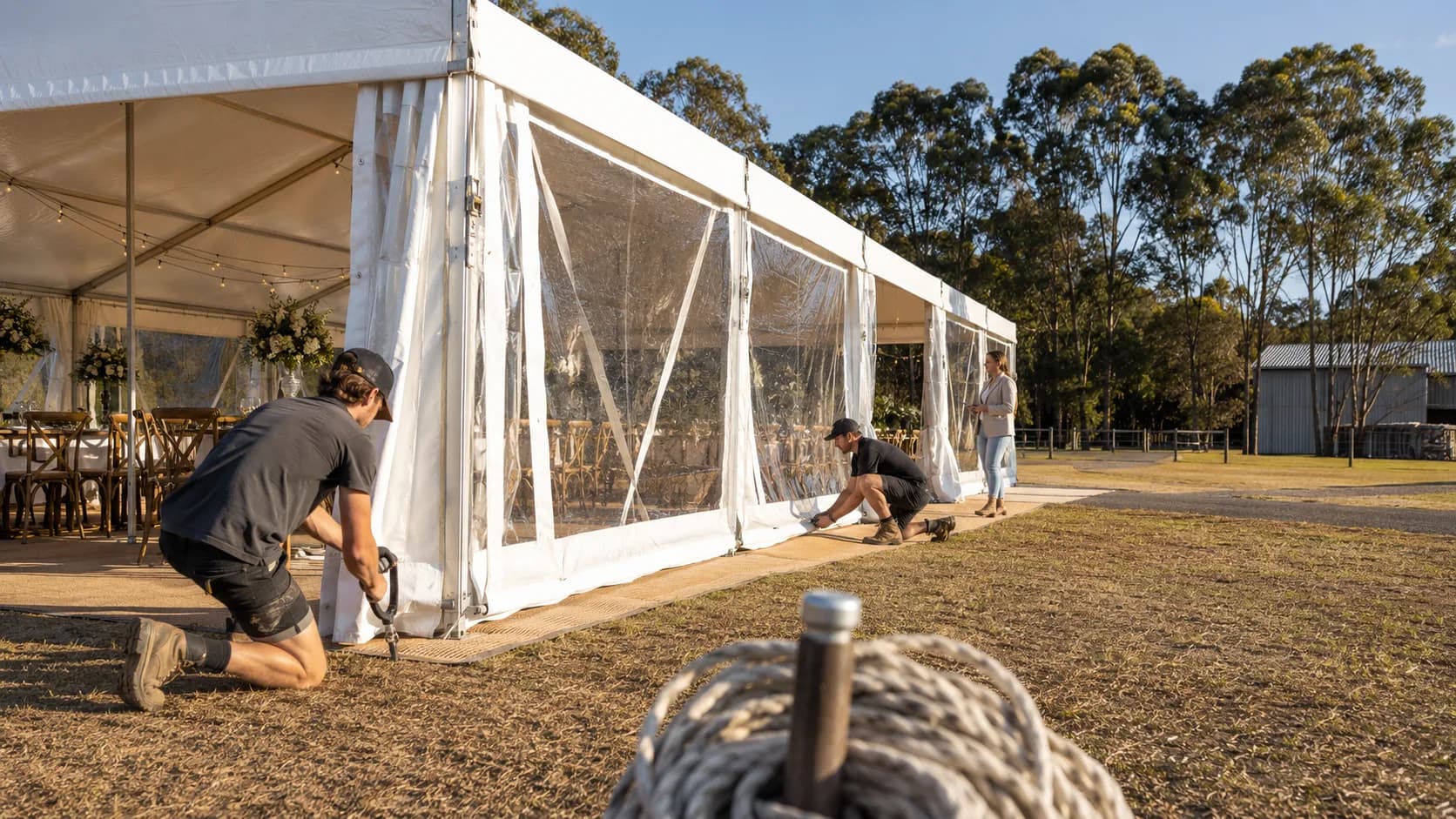 Crew securing a marquee wall at an outdoor event site in Australia