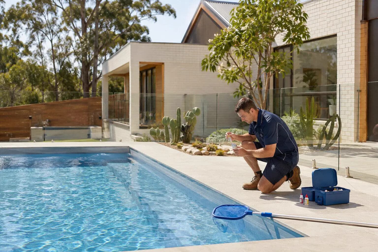 A pool technician testing the water at a backyard pool in Australia