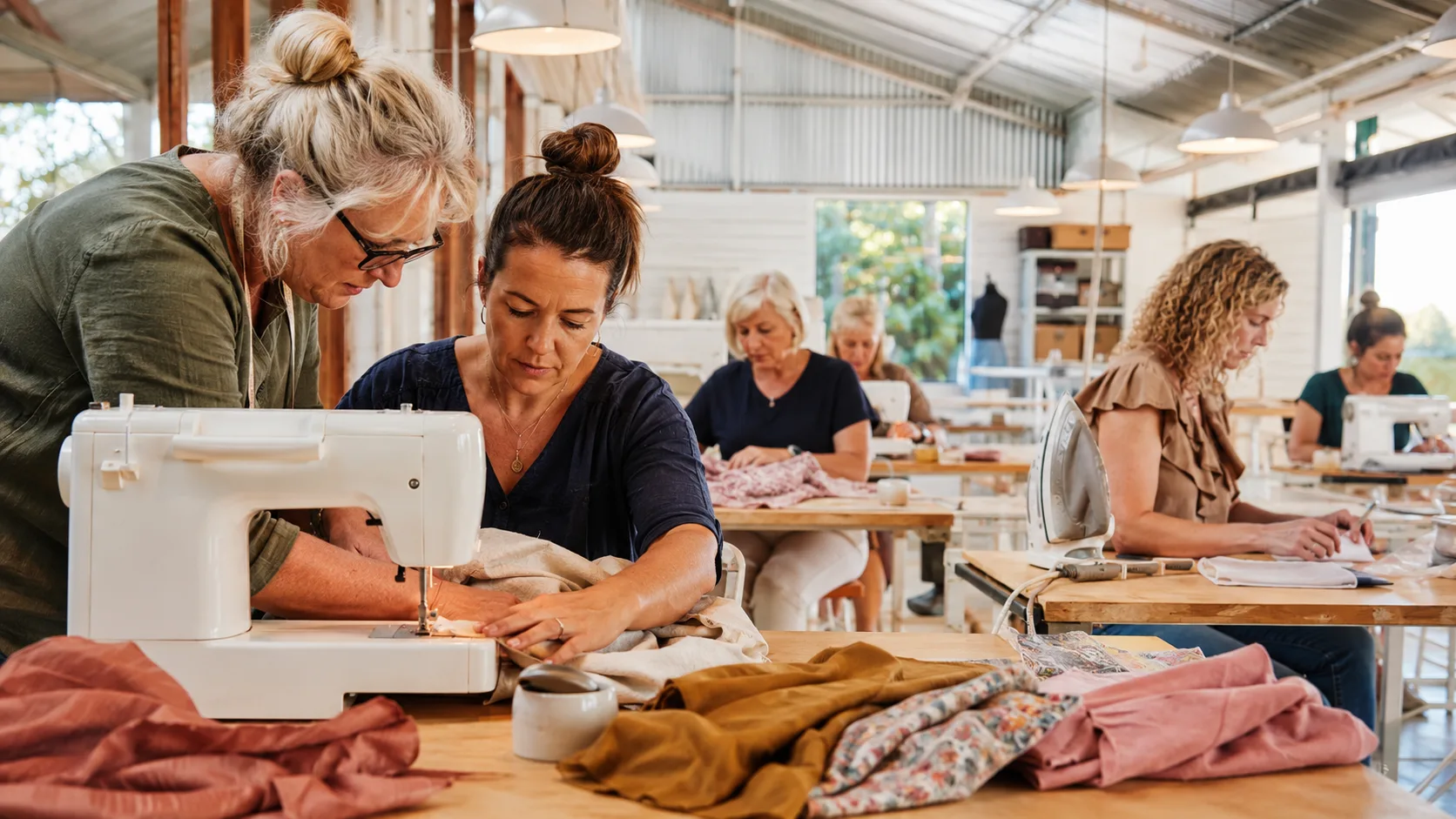 A tutor guides makers using sewing machines in an active dressmaking class in Australia