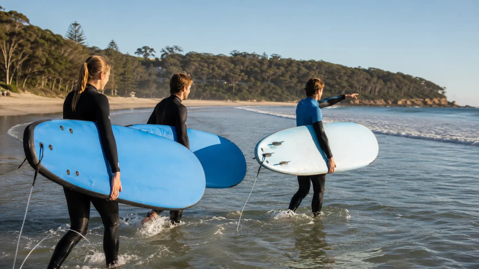 A surf instructor leads beginners into shallow water at a beach in Australia