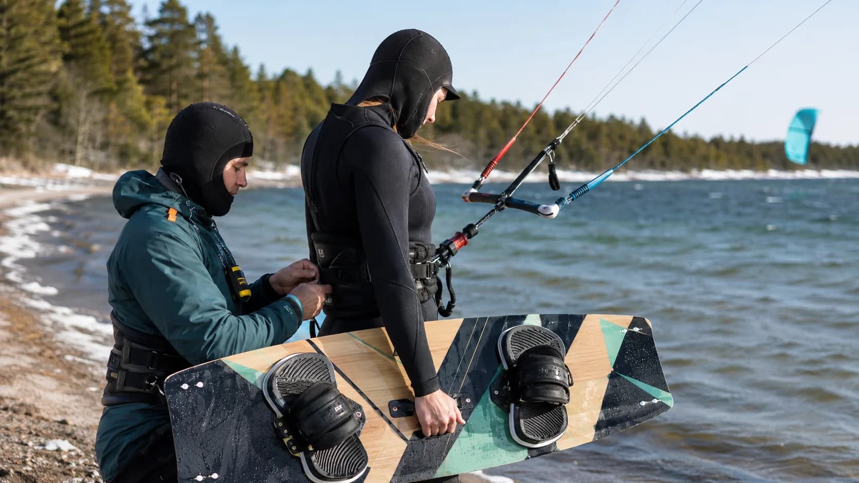 An kitesurf instructor checks kitesurf equipment beside a lake in Canada