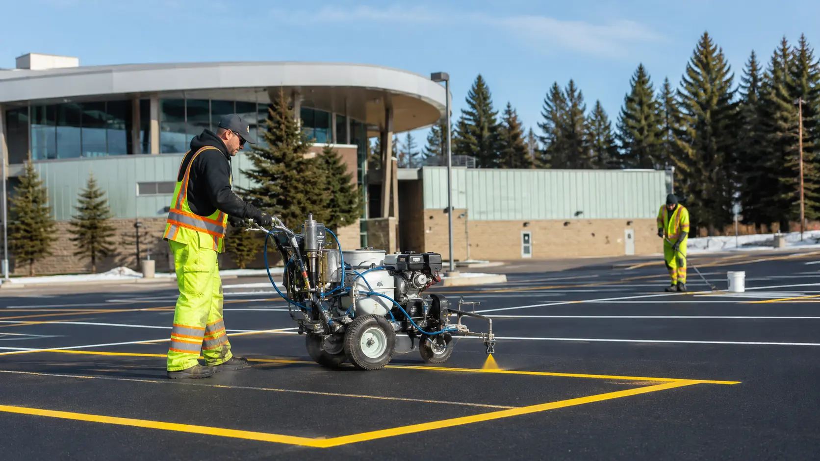 A worker marks yellow parking lines outside a Canadian commercial building