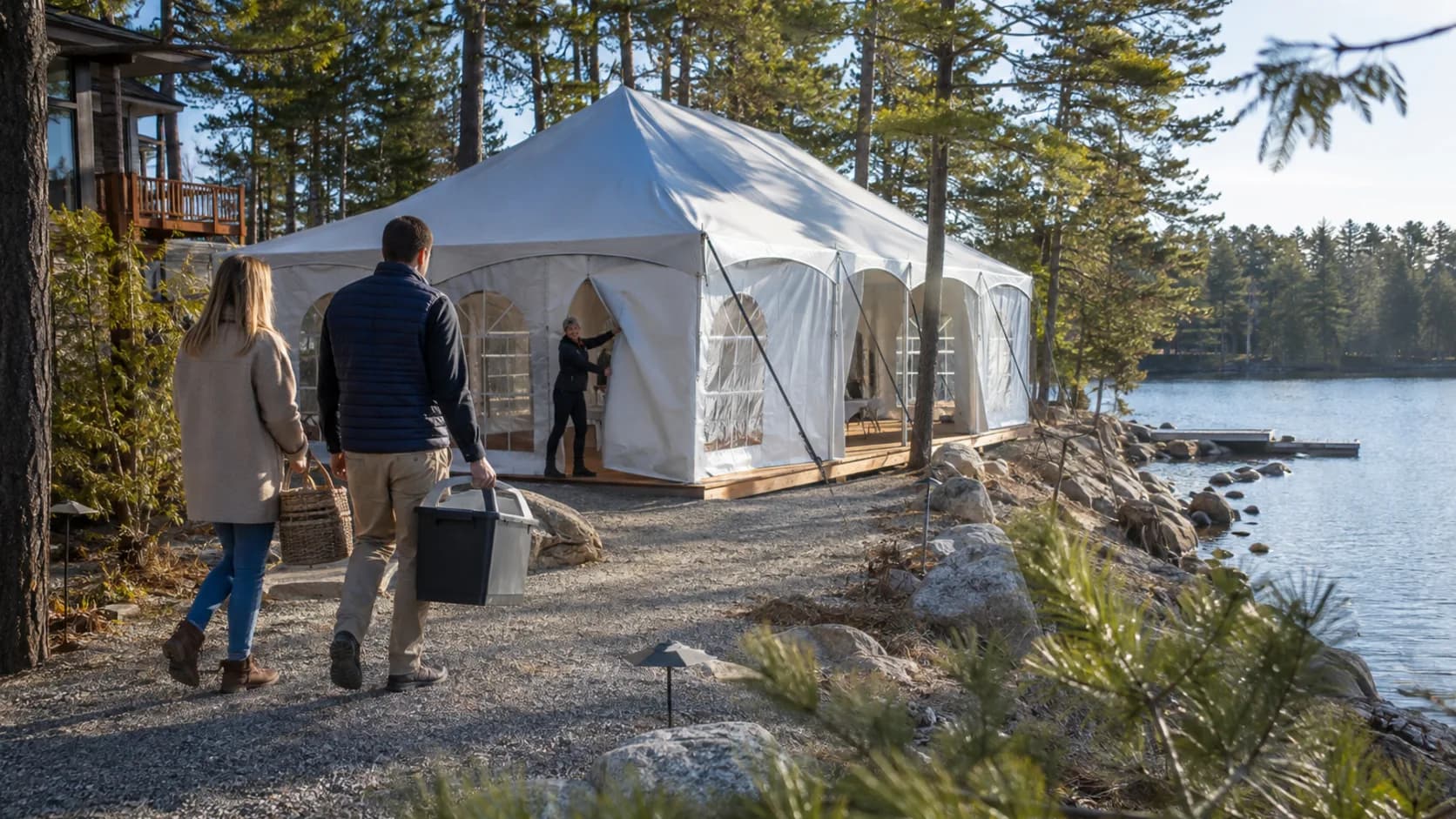 Operator carrying tent equipment beside a lakeside setup in Canada