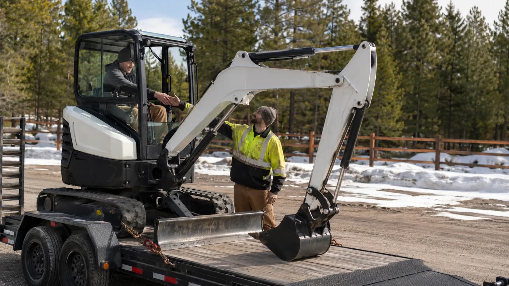 Technician inspecting a mini excavator at a snowy depot in Canada