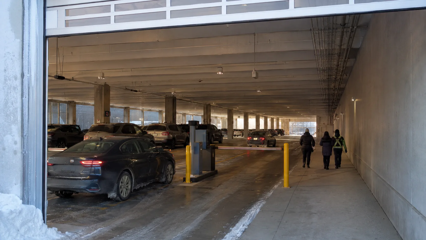 Drivers enter a snowy covered parking garage at first light