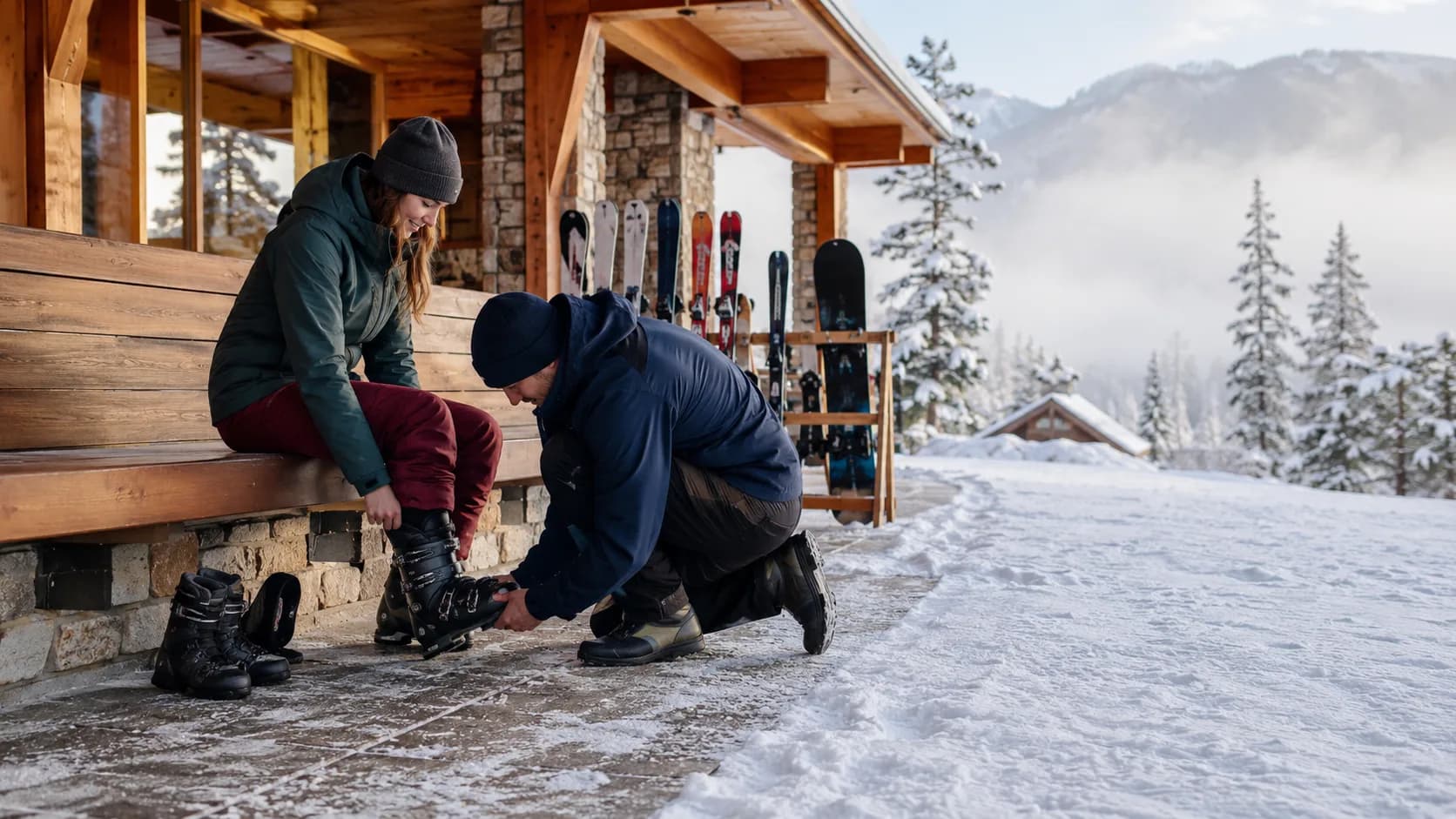 Technician checking ski bindings beside snowy mountains at a lodge in Canada