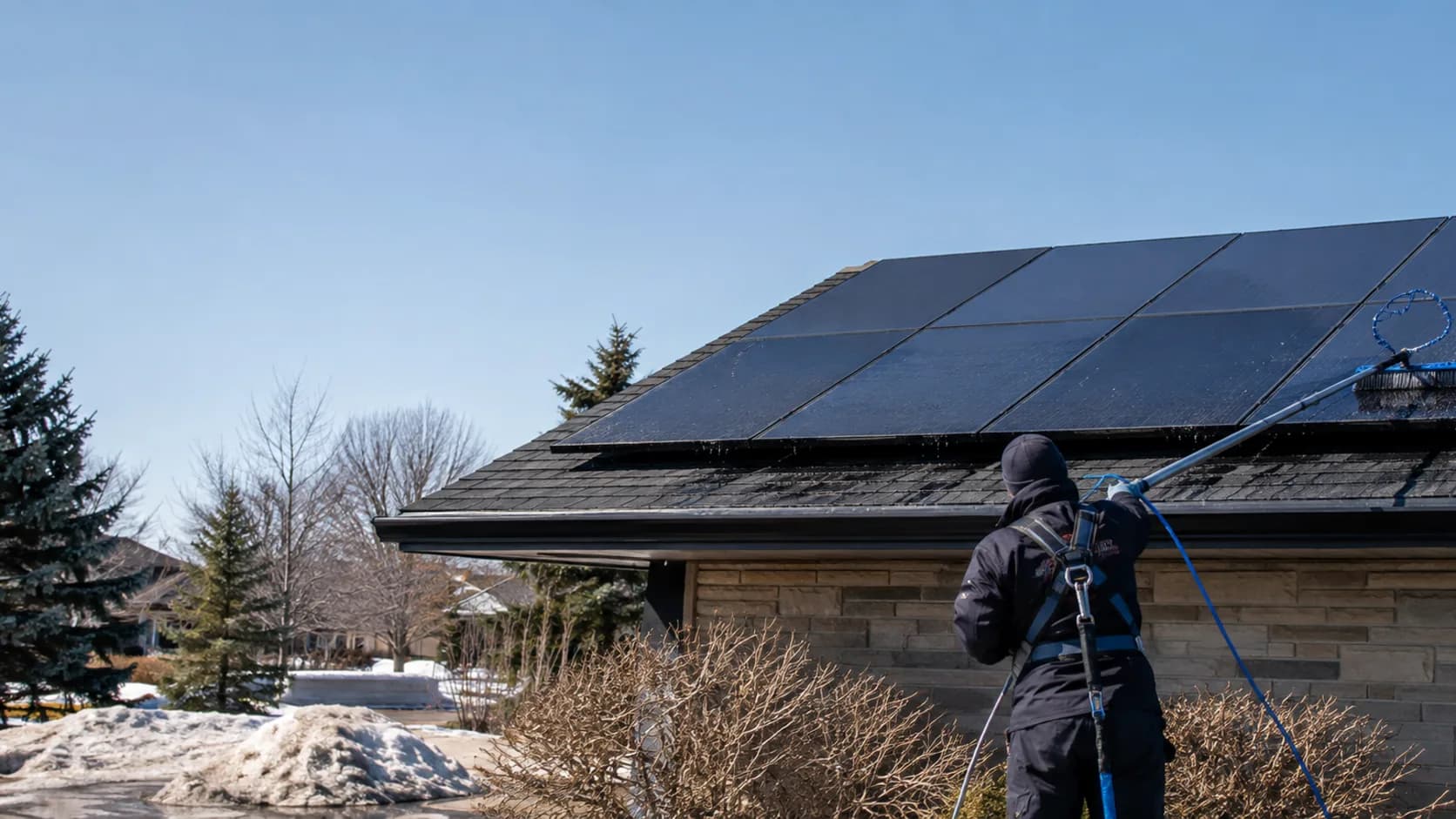 A cleaner washing a rooftop solar array in Canada