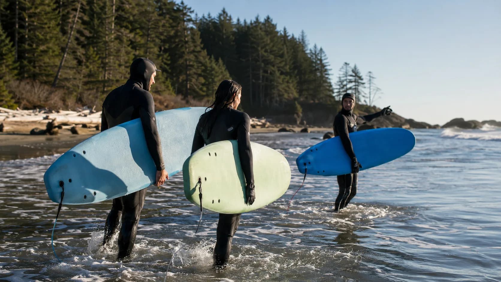 Cold-water surf students enter the sea with an surf instructor in Canada
