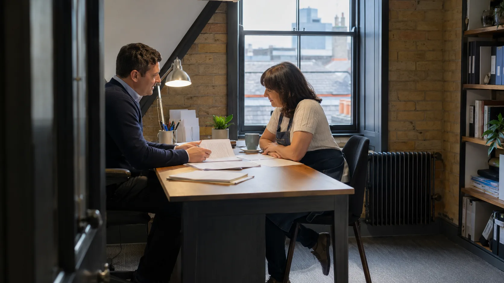 An accountant reviews financial papers with a small-business client in the UK