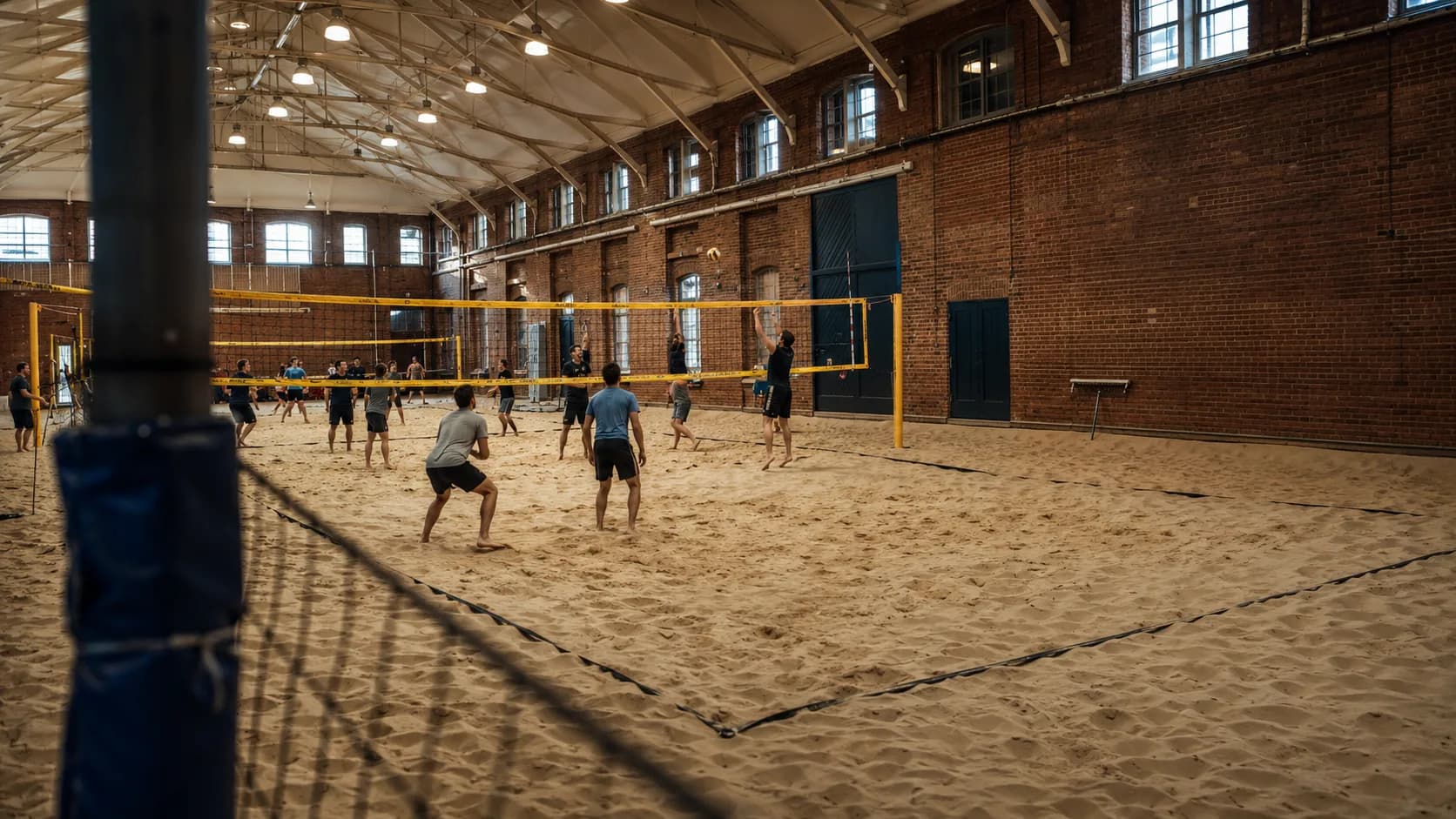 Players use bright sand courts beside a brick pavilion in the UK