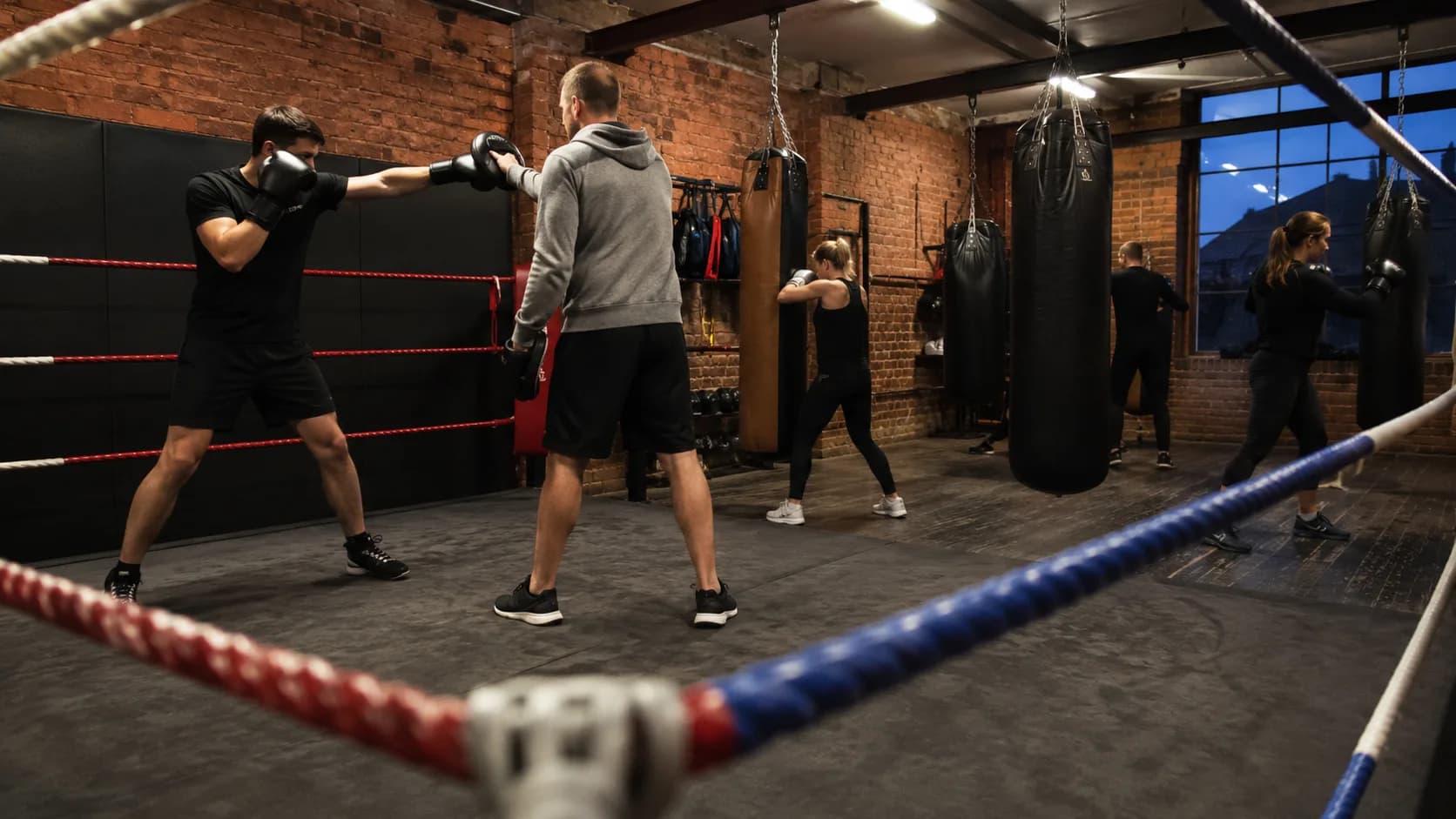 A boxing coach works the pads during an active gym class in the UK