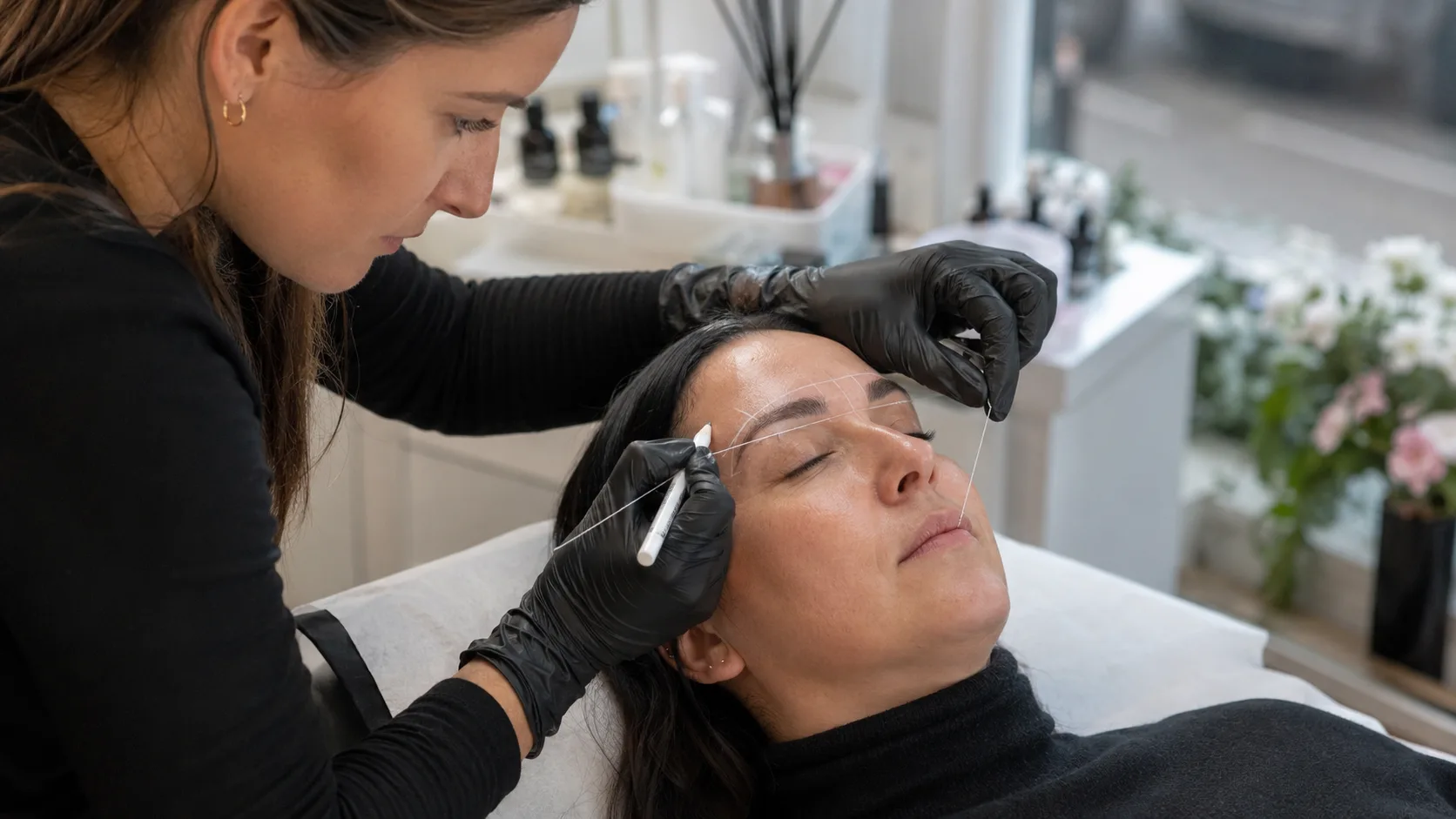 Cosmetic tattoo artist mapping a client’s brows inside a compact UK high-street studio