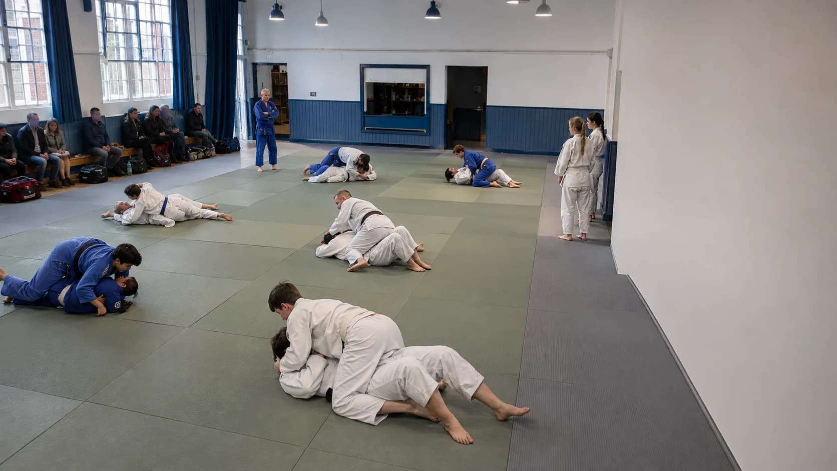Martial artists train across fitted mats inside a brick dojo in the UK