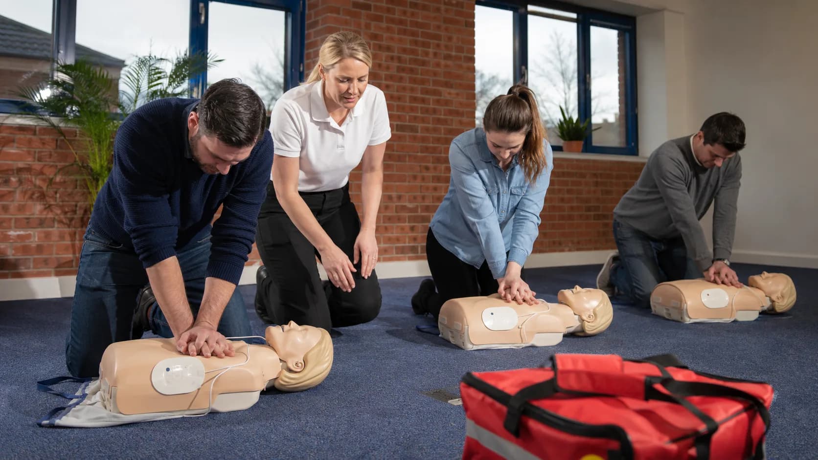 A trainer demonstrates practical first aid to an engaged adult class in the UK