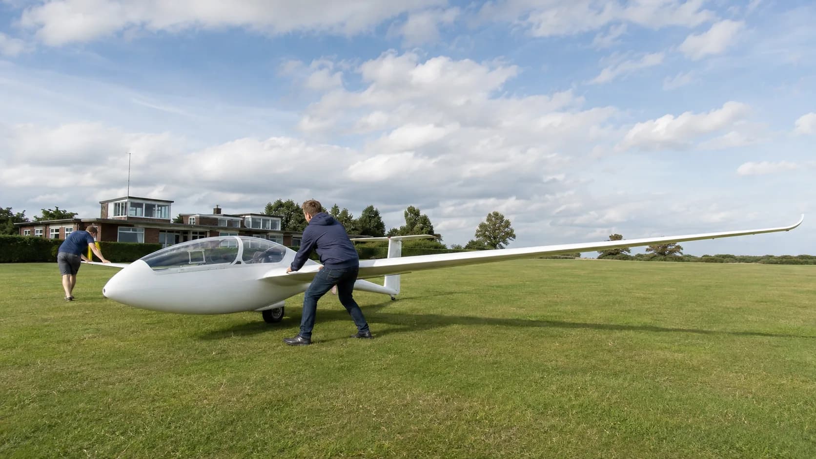 A glider waits at a UK launch point with a winch cable laid out across grass