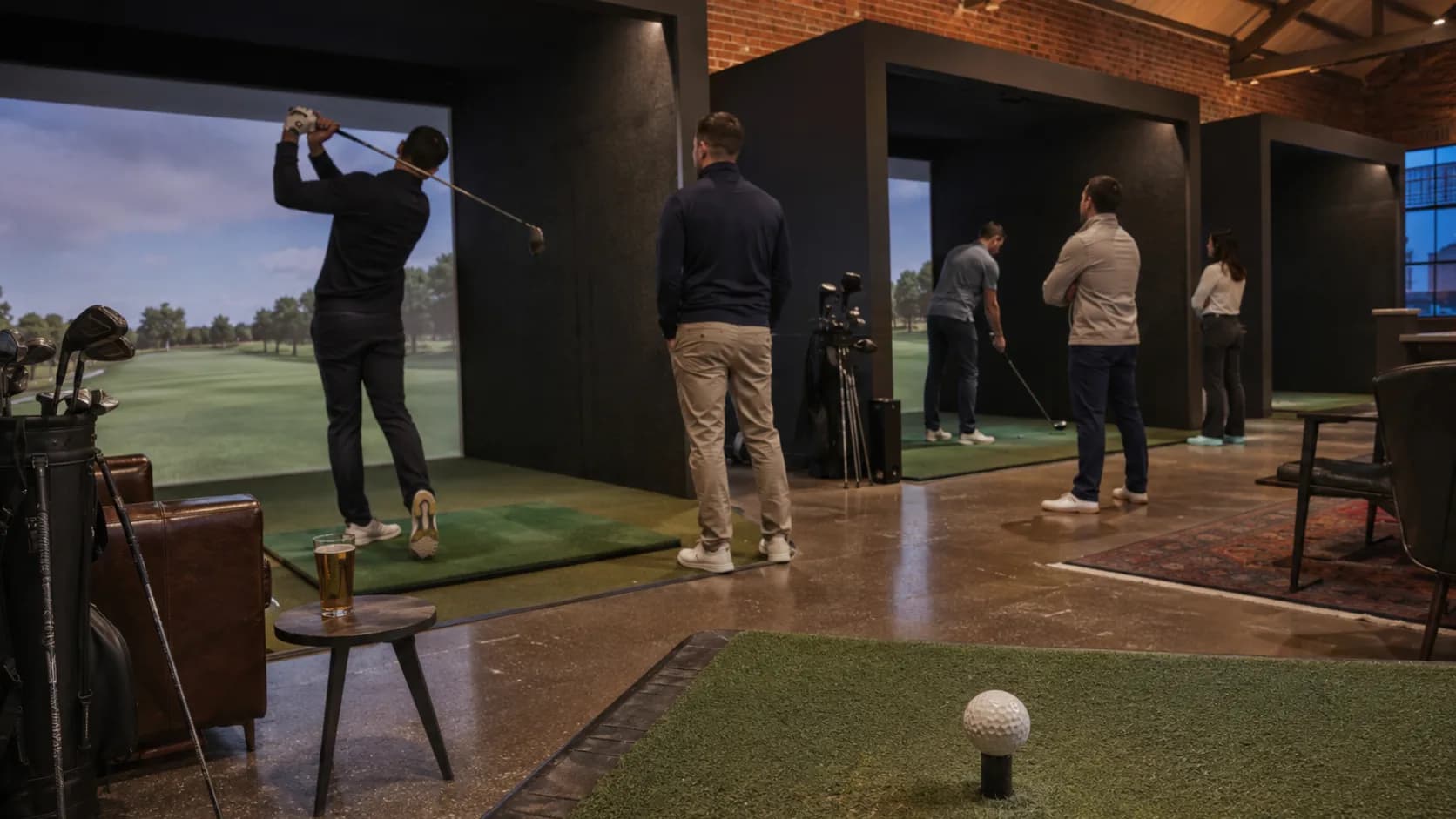 Golfers play an evening simulator league inside brick bays in the UK