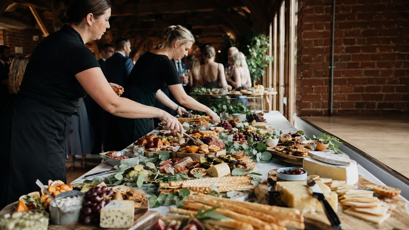 the UK grazing-table team replenishing a reception in a brick venue