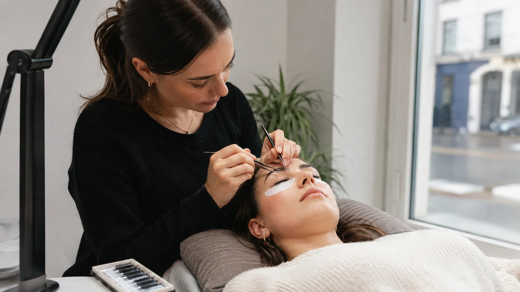 Lash artist applying extensions for a client inside a compact UK high-street studio