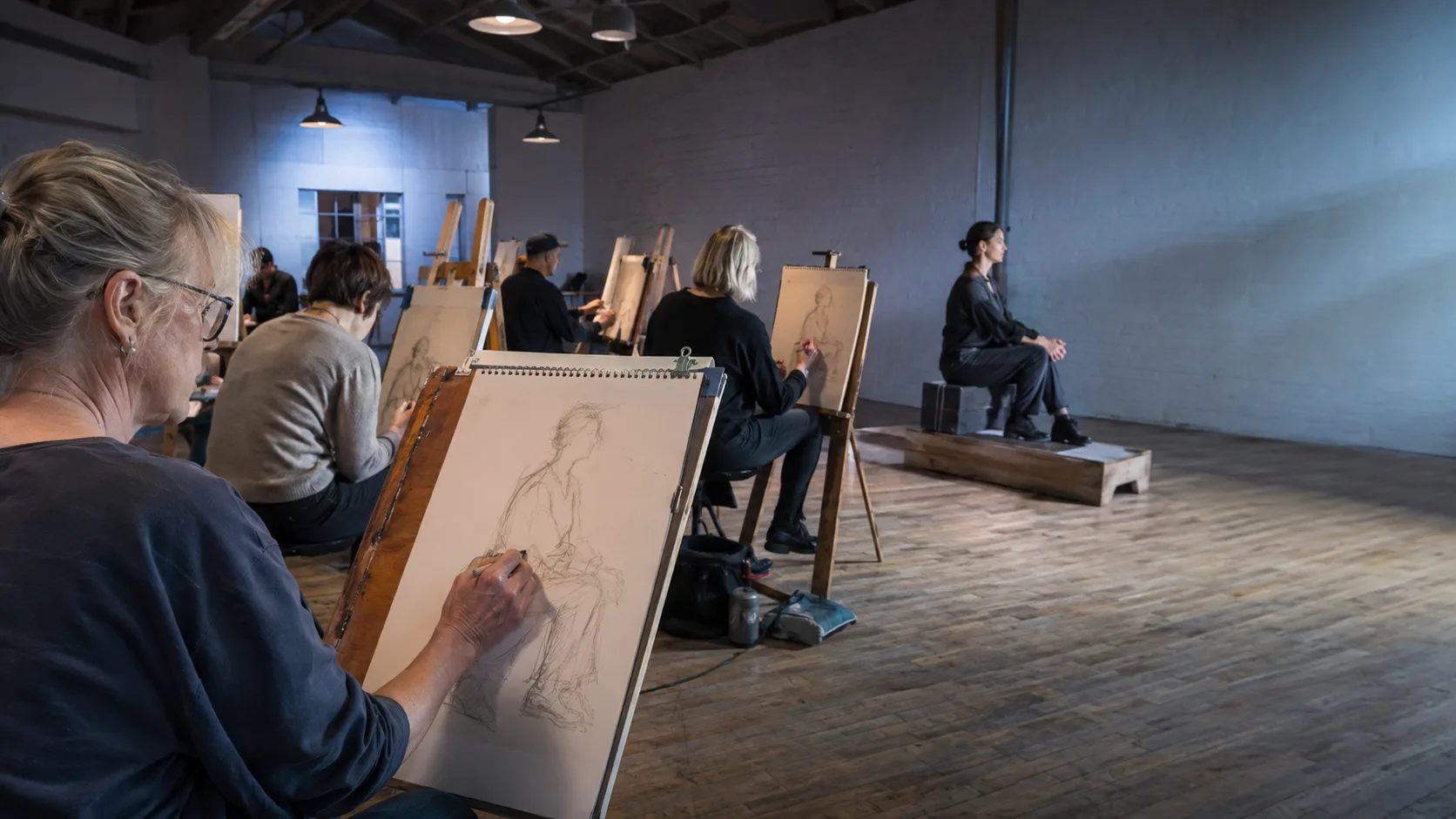 Life-drawing class working from a clothed model in a studio in the UK