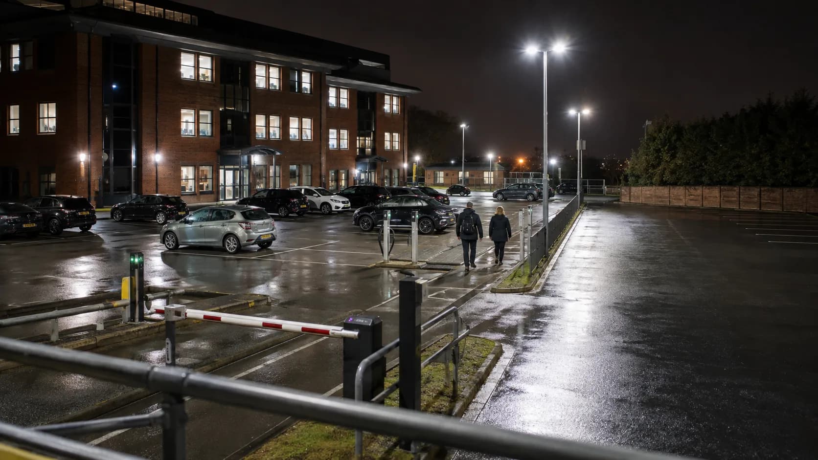 Drivers use a floodlit brick office car park after rain