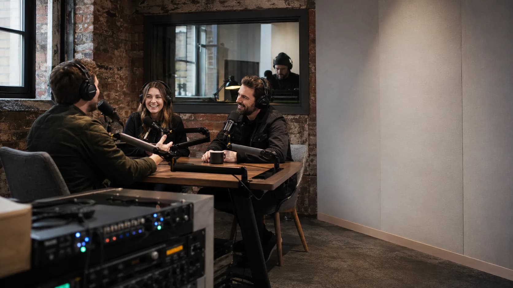 Two presenters record a lively discussion in a working UK podcast studio