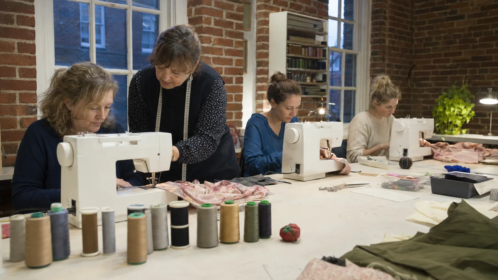 A tutor guides makers using sewing machines in an active dressmaking class in the UK