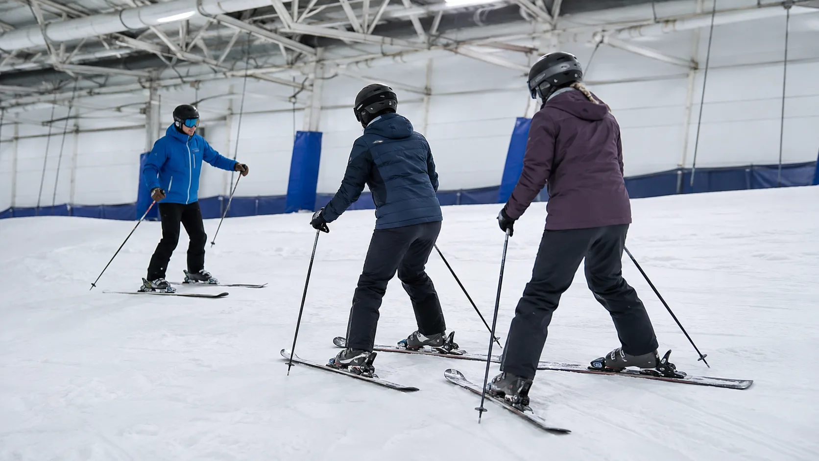 Instructor coaching beginner skiers inside a snow centre in the UK