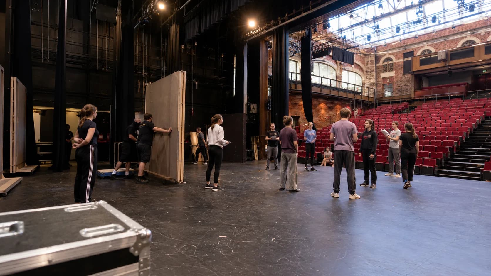 A company performs on stage before a full traditional theatre