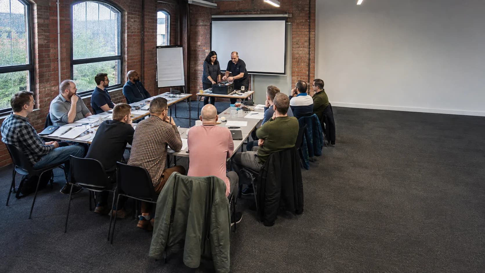 A facilitator leads an occupied training session around flexible tables