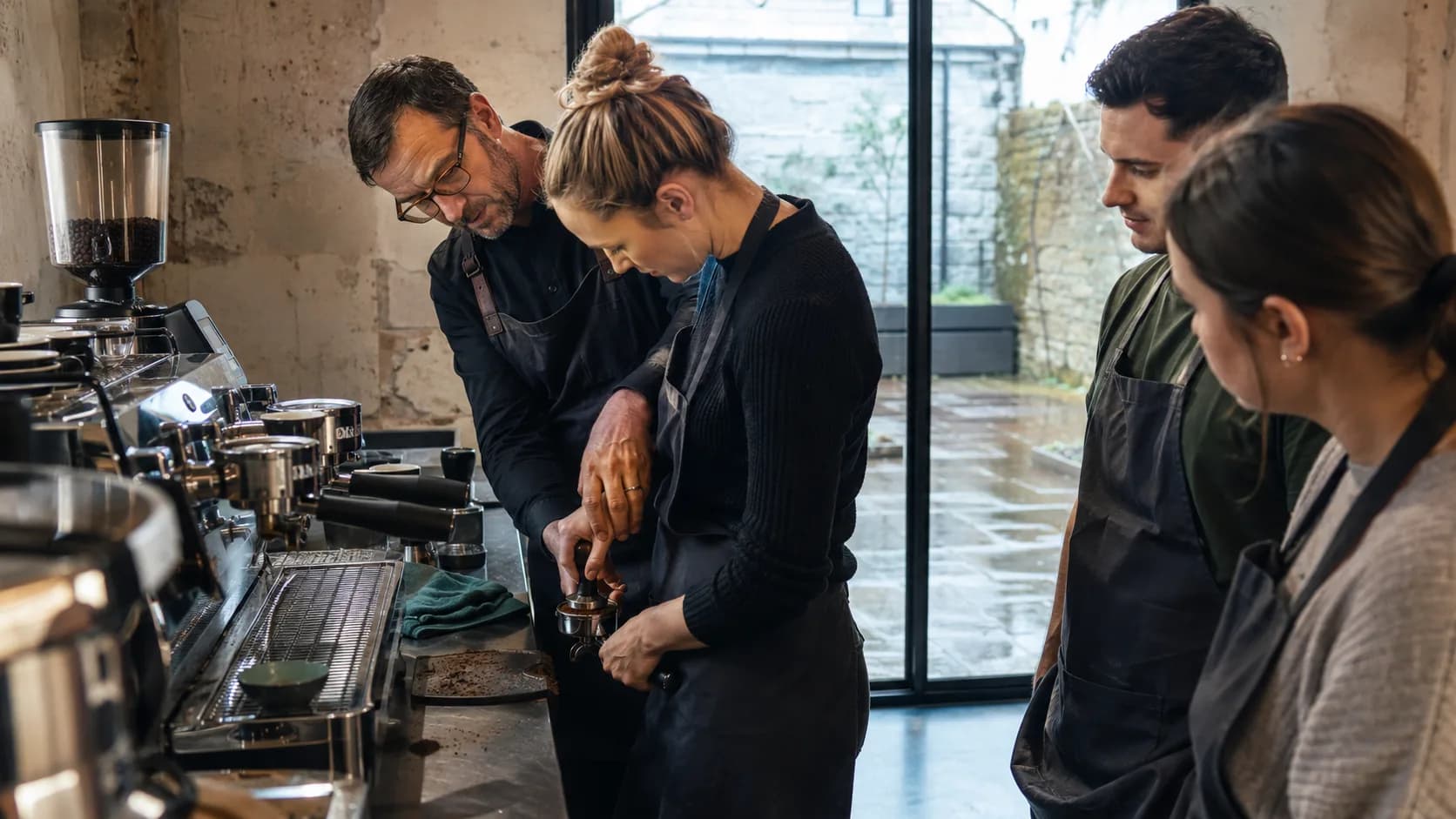 A coffee trainer coaches learners at commercial espresso machines during class in Ireland