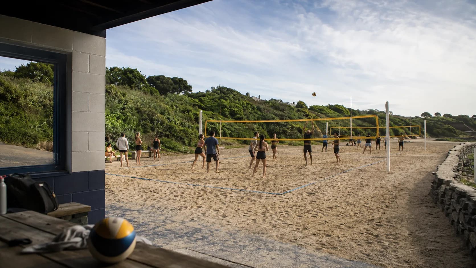 Teams play beach volleyball beneath coastal light at an Irish venue