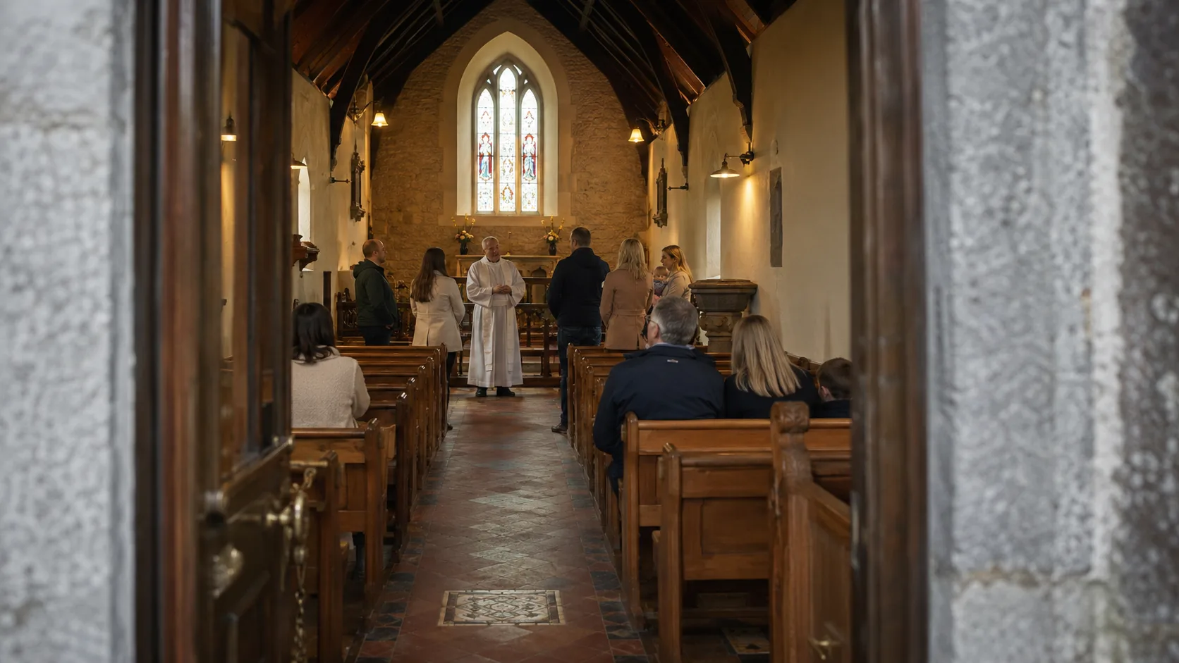 A wedding party gathers inside a softly lit Irish church