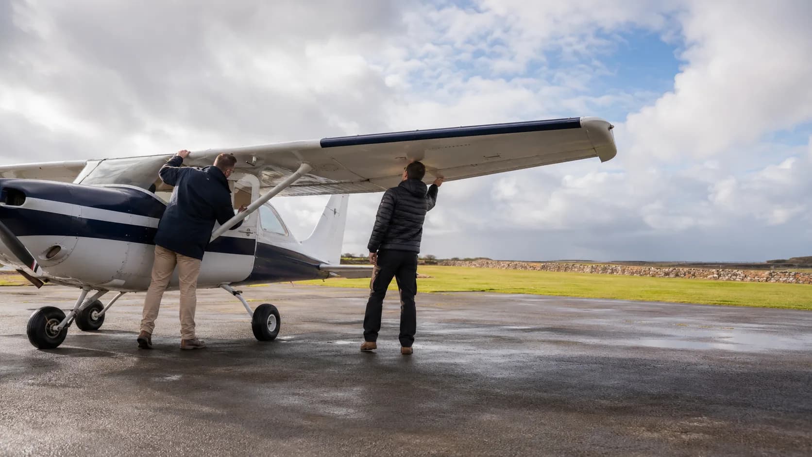 A training aircraft waits on an Irish airfield apron beneath a soft grey sky