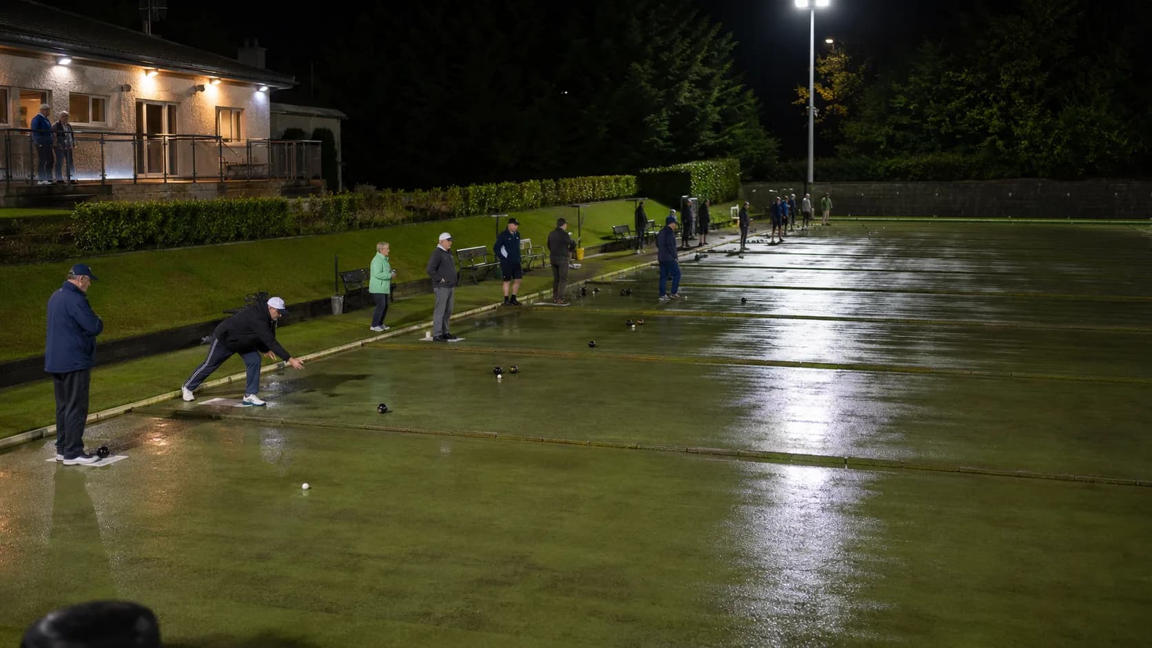 Players gather around marked lawn bowls rinks at an Irish club