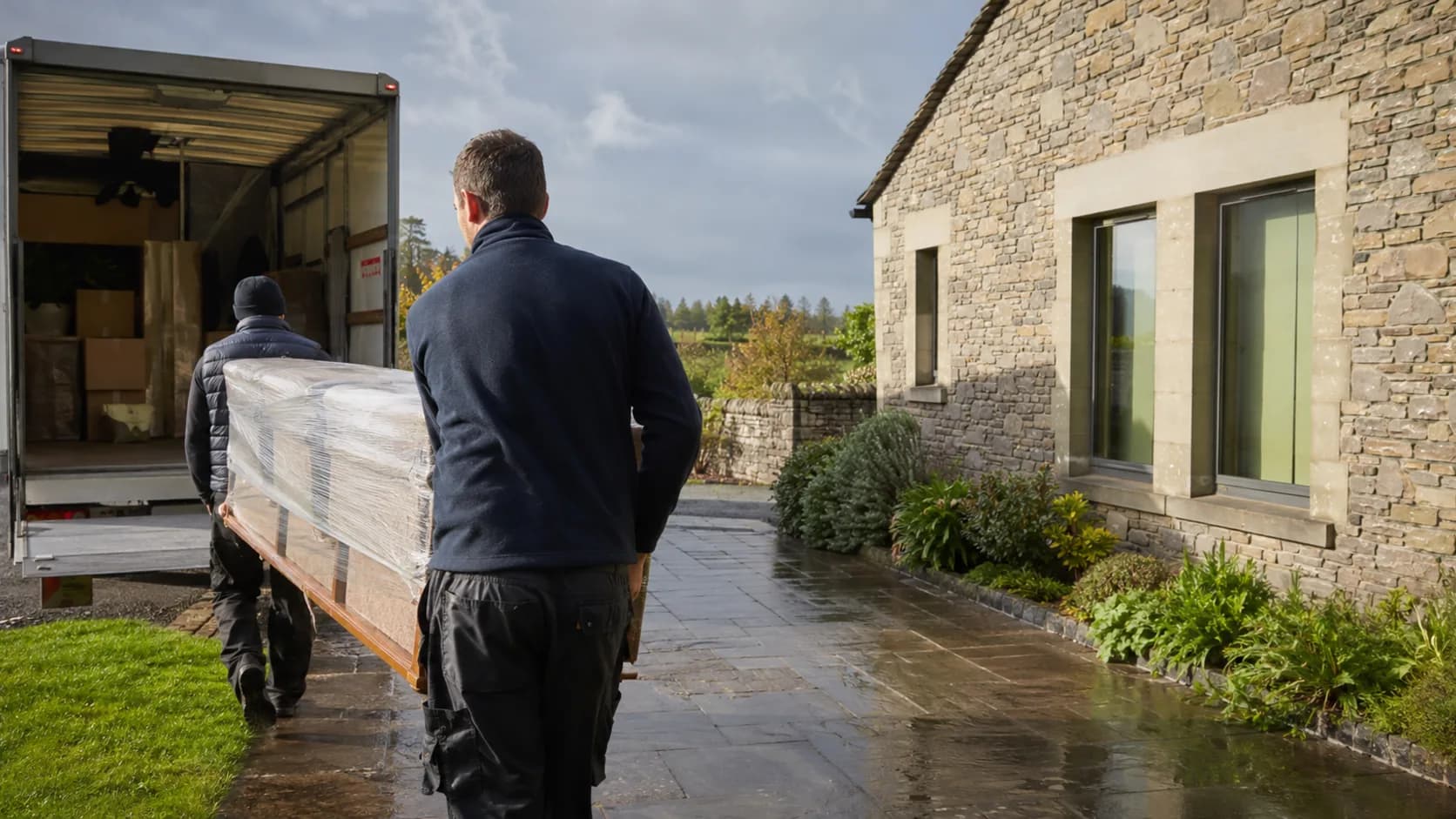 A moving crew carrying a sofa into a truck outside a home in Ireland