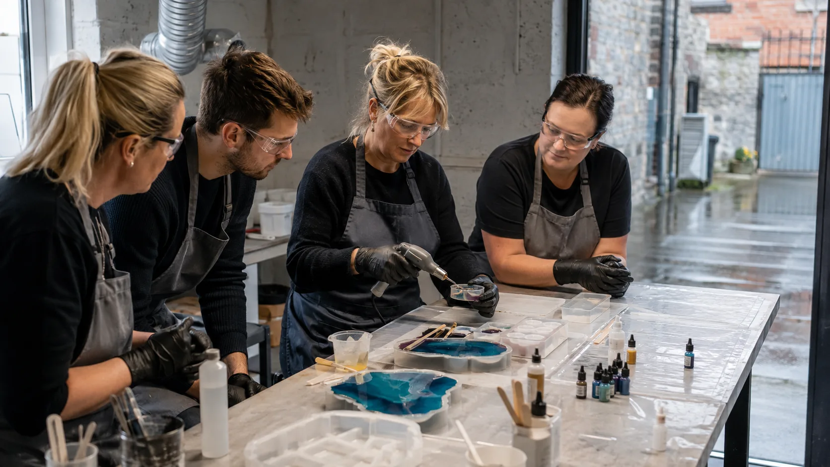An artist tutor guides a resin pour at ventilated workshop stations in Ireland