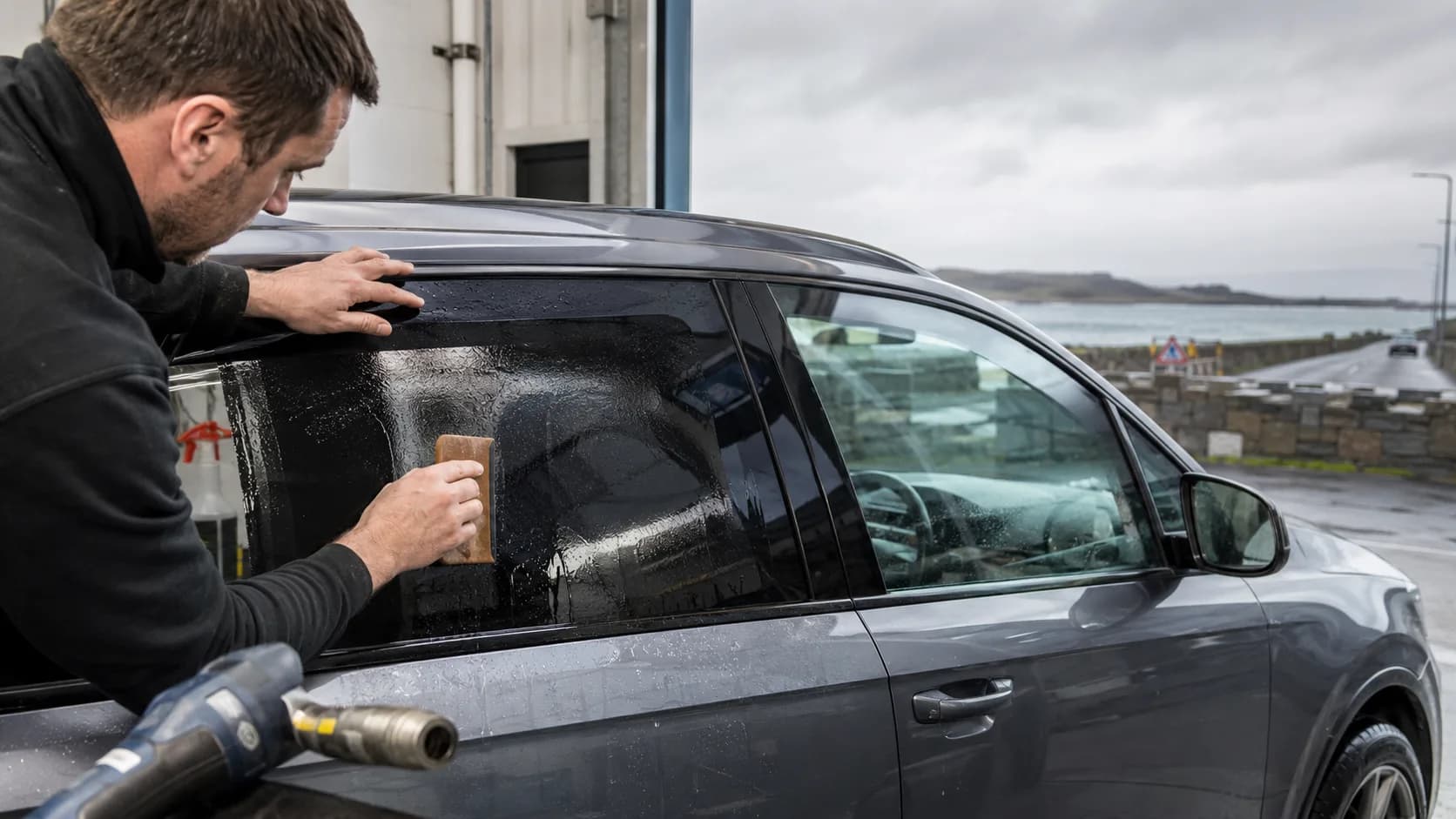 A tinter squeegeeing film onto a window in Ireland