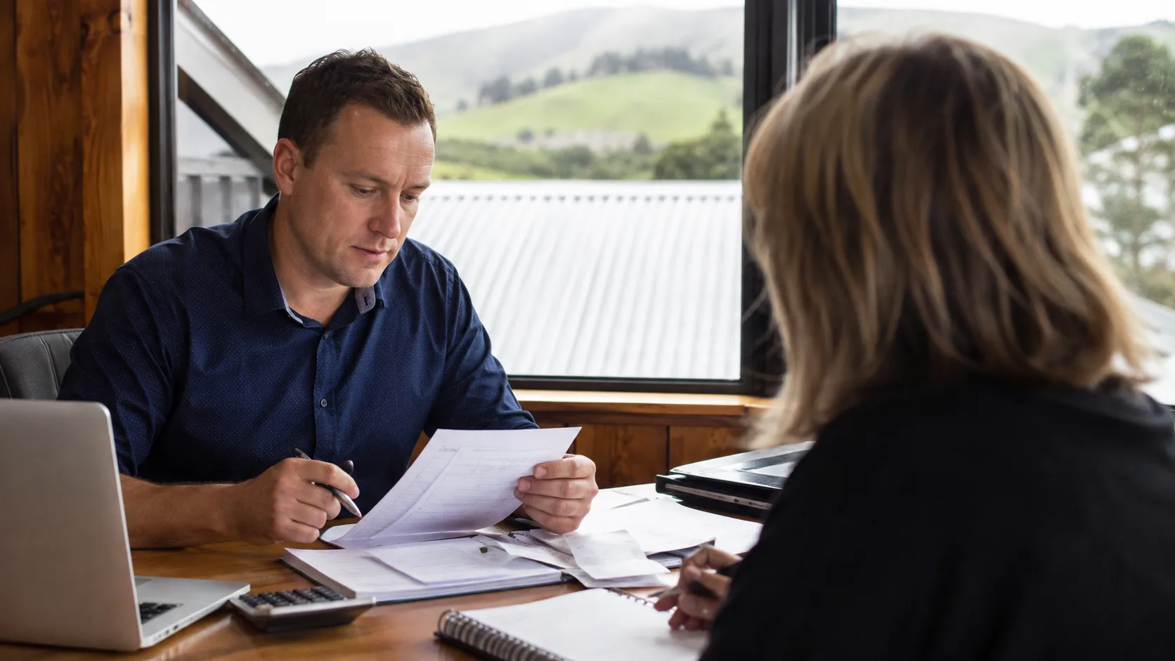 An accountant reviews financial papers with a small-business client in New Zealand