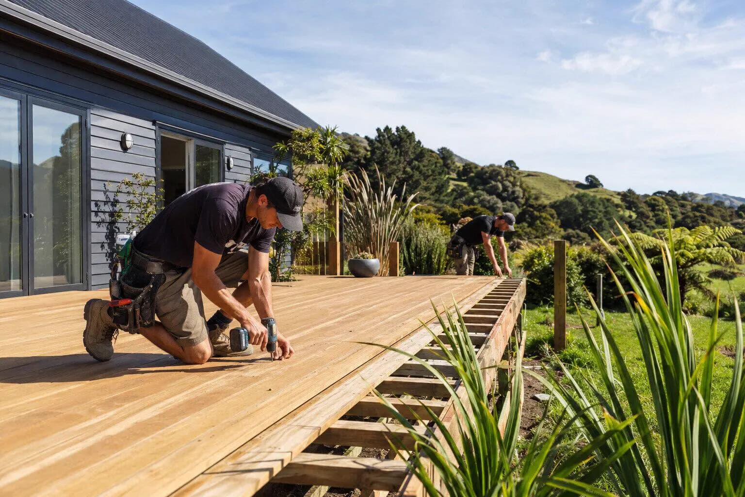 A fencer building a timber deck behind a house in New Zealand