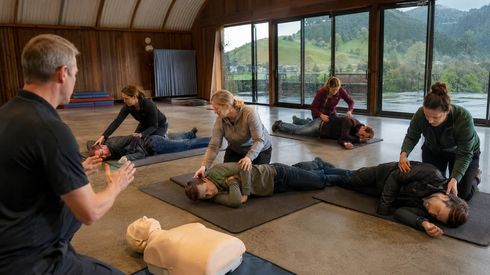 A trainer demonstrates practical first aid to an engaged adult class in New Zealand
