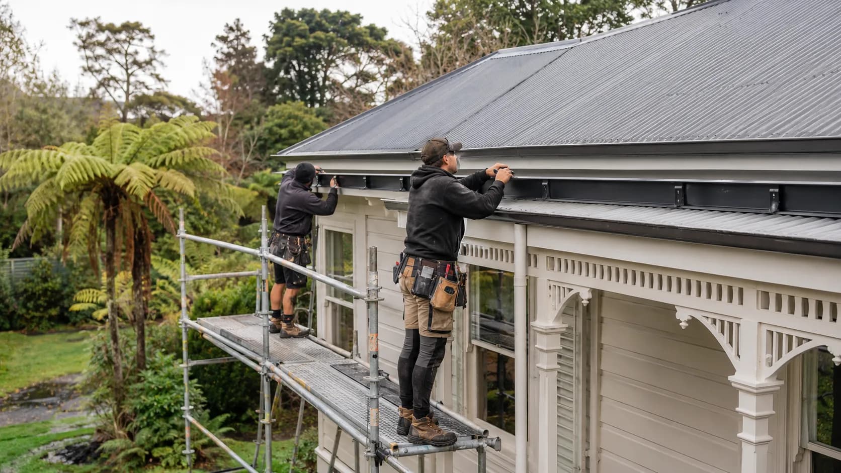 A fitter hanging a new gutter run in New Zealand